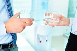 people having glass in their hands in front of office water cooler